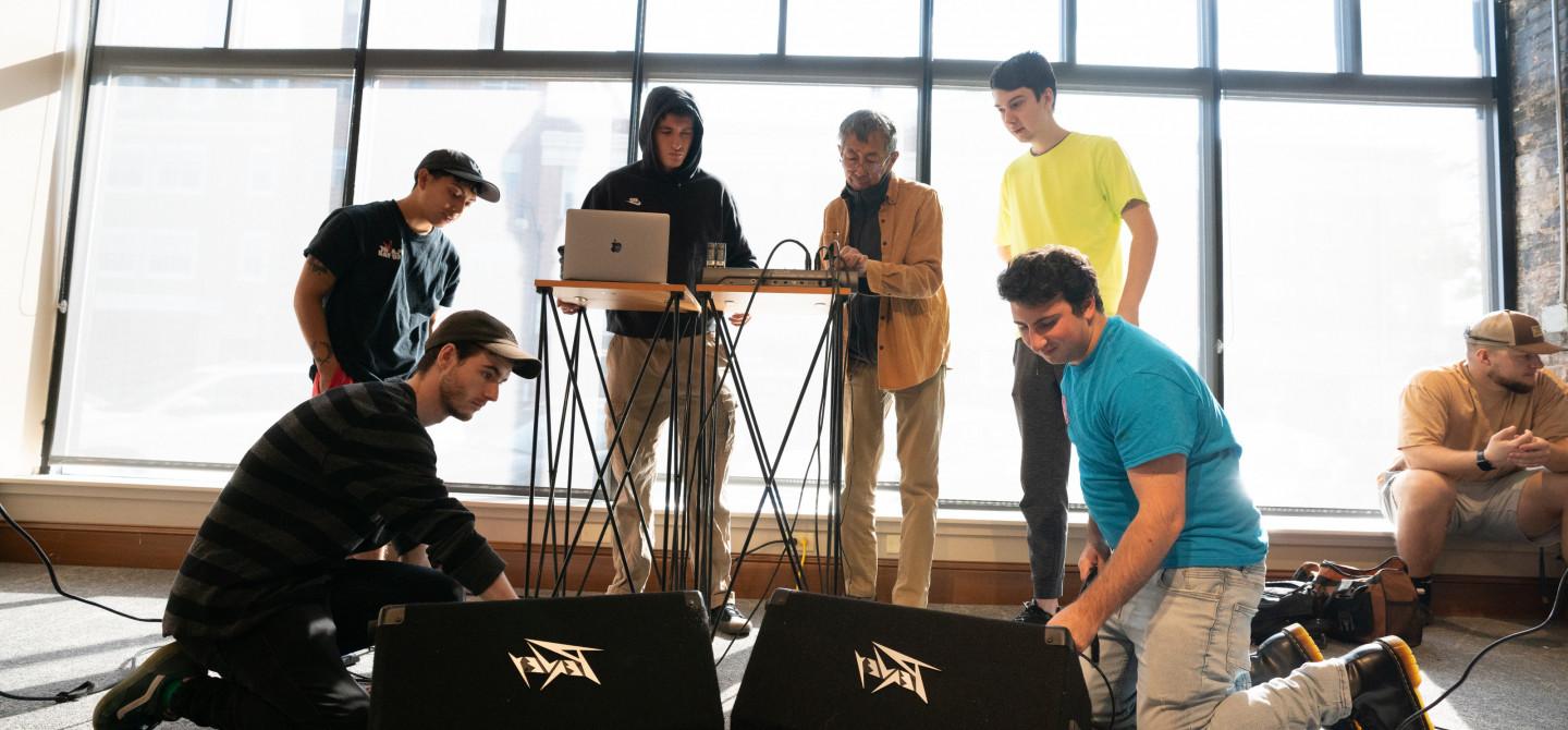 Students work with a professor on how to best arrange sound equipment.